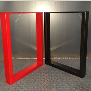 May include: Two metal table legs, one red and one black. The legs are made of square tubing and have a simple, modern design.