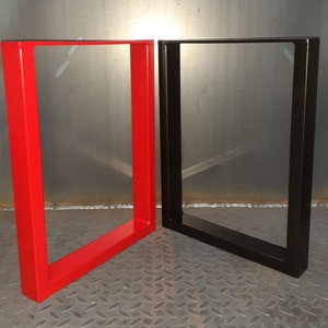 May include: Two metal table legs, one red and one black. The legs are made of square tubing and have a simple, modern design.