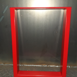 May include: Red metal table legs with a square frame. The legs are made of thick metal and have a smooth, painted finish.