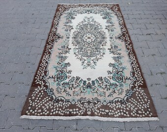 May include: A vintage rug with a floral pattern in shades of brown, cream, and blue. The rug has a fringed edge and a central medallion design.