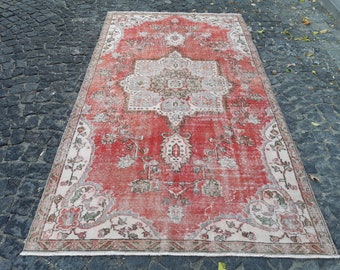 May include: A vintage red and cream rug with a floral pattern. The rug has a distressed look and is made of wool.