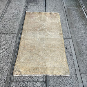 Op de afbeelding: Een lichtbeige rechthoekig tapijt met een subtiel patroon. Het tapijt ligt plat op een grijs betonnen oppervlak.