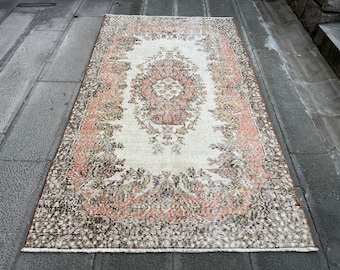 May include: A vintage rug with a floral pattern in shades of brown, pink, and cream. The rug has a distressed look and is perfect for adding a touch of bohemian style to any room.