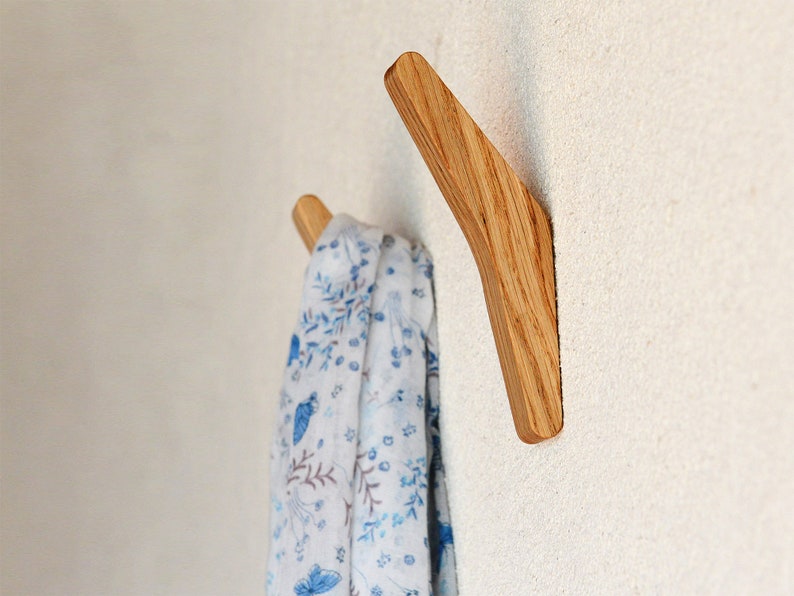 May include: A wooden wall hook with a curved design. A white scarf with a blue floral pattern is hanging on the hook.