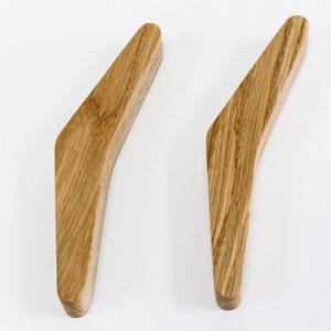 May include: Two wooden handles with a curved design. The handles are made of light brown wood with a natural grain pattern.