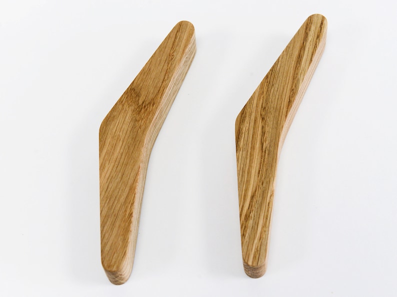 May include: Two wooden handles with a curved design. The handles are made of light brown wood with a natural grain pattern.