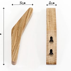 May include: A wooden wall hook with a curved design. It measures 5 inches wide, 1.5 inches tall, and 2 inches deep. The hook has two holes for mounting.