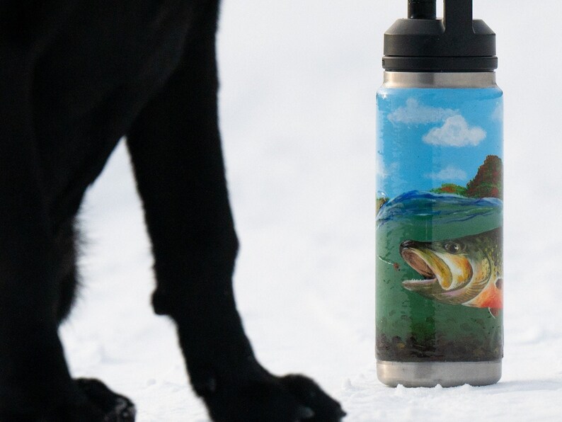 May include: Stainless steel water bottle with a black lid and a wrap-around design. The design features a fish swimming in water, with a blue sky and green landscape in the background.