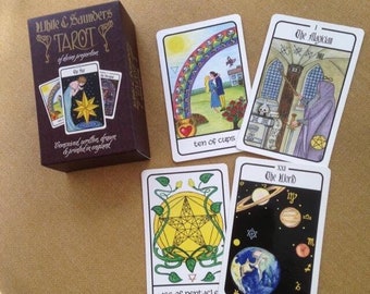 May include: A tarot card deck with a purple box and several cards displayed. The box reads "White & Saunders Tarot" and "Conceived, written, drawn & printed in England." The cards feature illustrations and titles like "Ten of Cups" and "The Magician."