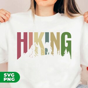 May include: White sweatshirt with a colorful graphic design that says "HIKING" with a silhouette of a hiker, mountains, and trees.