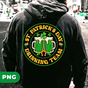 Pode incluir: Camisola de capuz preta com um gráfico circular verde, amarelo e branco que diz "St. Patrick's Day Drinking Team" com um trevo e duas canecas de cerveja.