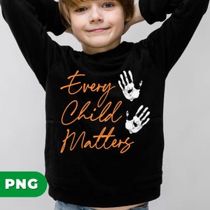 May include: Black sweatshirt with the text "Every Child Matters" in orange script. Two white handprints are above the text. The sweatshirt has a front pocket.