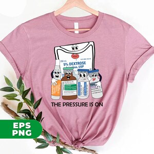 May include: A pink t-shirt with a graphic of a medical IV bag and several vials of medication. The IV bag has a face and the vials have faces. The text "THE PRESSURE IS ON" is printed below the graphic.