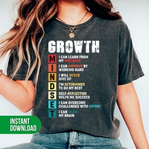 Op de afbeelding: Een grijs T-shirt met het woord "GROWTH" in witte letters en het woord "MINDSET" in kleurrijke letters. De letters in "MINDSET" worden elk gevolgd door een zin die een positieve mindset beschrijft.