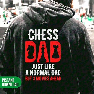 Puede incluir: Sudadera negra con texto blanco que dice "Chess Dad" y texto rojo que dice "Just like a normal dad but 3 movies ahead". El texto está rodeado de piezas de ajedrez.
