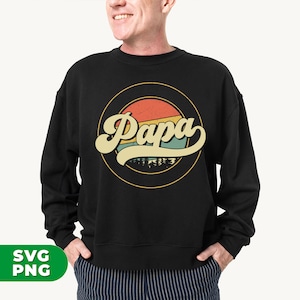 Puede incluir: Sudadera negra con un gr&aacute;fico retro de un sol con la palabra "Papa" en una fuente amarilla, naranja y azul.