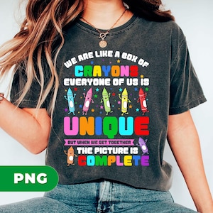 May include: Dark gray t-shirt with the text "WE ARE LIKE A BOX OF CRAYONS EVERYONE OF US IS UNIQUE BUT WHEN WE GET TOGETHER THE PICTURE IS COMPLETE." The shirt features colorful crayon illustrations.