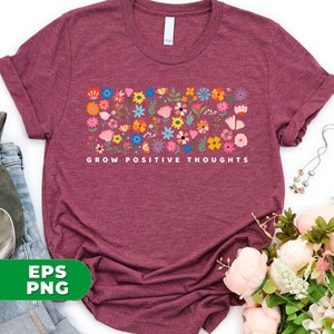 May include: A maroon t-shirt with a floral design and the text "Grow Positive Thoughts" printed on the front.