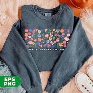 May include: A dark gray sweatshirt with a colorful floral design and the text "Grow Positive Though" printed on the front.