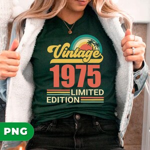 May include: Dark green t-shirt with a retro design that reads "Vintage 1975 Limited Edition." The design features a sunset with palm trees and a rainbow. The text is in yellow and orange.