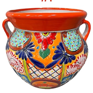 May include: Orange ceramic planter with a floral design. The planter has two handles and is decorated with colorful flowers and geometric patterns. The text "Orange #1" is written above the planter.
