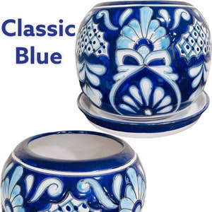 May include: Two blue and white ceramic flower pots with a traditional Mexican Talavera design. The pots have a round shape and a saucer base. The design features blue and white floral patterns.