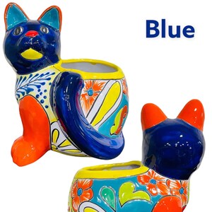 May include: Blue ceramic cat planter with colorful floral designs. The planter has a wide opening for planting.