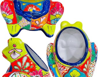 Può includere: Un vaso da fiori in ceramica verde lime a forma di rana con disegni floreali colorati. La rana è seduta con le gambe incrociate e ha un ampio sorriso con i denti. Il vaso è perfetto per aggiungere un tocco di stravaganza alla tua decorazione domestica.