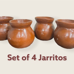 May include: Set of four terracotta brown jarritos, traditional Mexican clay cups, arranged in a row on a light brown surface. The text "Set of 4 Jarritos" is printed below the cups.