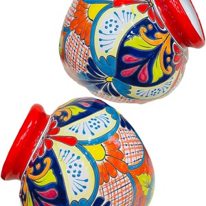 May include: Two red and white ceramic pots with colorful floral designs. The pots are hand-painted with blue, yellow, orange, and pink flowers. The pots are perfect for adding a touch of Mexican style to your home.