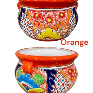 May include: Two terracotta flower pots with colorful floral designs. The top pot is orange with red, yellow, and white flowers. The bottom pot is orange with blue, green, and yellow flowers. The text "Orange" is printed below the pots.