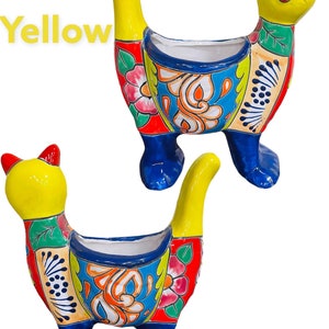 May include: Two colorful ceramic cat planters with yellow, blue, red, and green floral designs. The cats have yellow heads and blue legs. The word "Yellow" is written in the top left corner of the image.