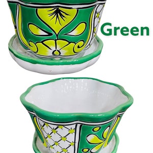 May include: Green ceramic planter with a white interior and a matching saucer. The planter has a scalloped rim and features a floral design with green, yellow, and white accents.