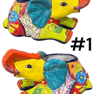 May include: Two colorful ceramic elephant planters with a blue, green, yellow, red, and orange painted design. The planters are sitting on a white surface. #1
