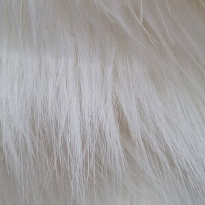 May include: Close-up of white fluffy feathers. The feathers are soft and delicate, with a slight sheen.