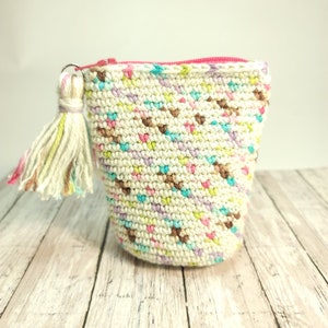 May include: A small crocheted zipper pouch with a colorful confetti pattern and a white tassel. The pouch is made with a white yarn with pops of pink, blue, green, and brown.