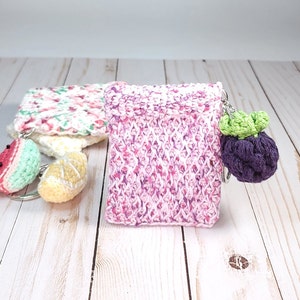 May include: A pink and white crocheted coin purse with a purple crocheted grape charm attached to a silver key ring.