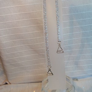 May include: Two silver bra straps with clear rhinestone embellishments and triangle-shaped metal clasps.