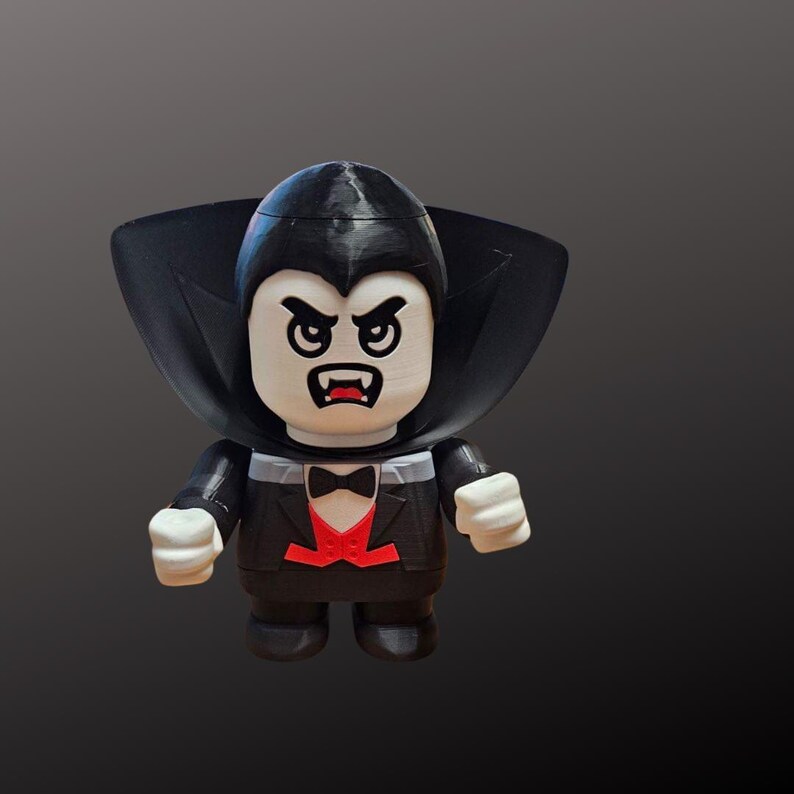 May include: A 3D-printed vampire figurine with a black cape, tuxedo, and bow tie. The vampire has an angry expression with sharp fangs. The figure is painted in black, white, and red, and is a collectible item.