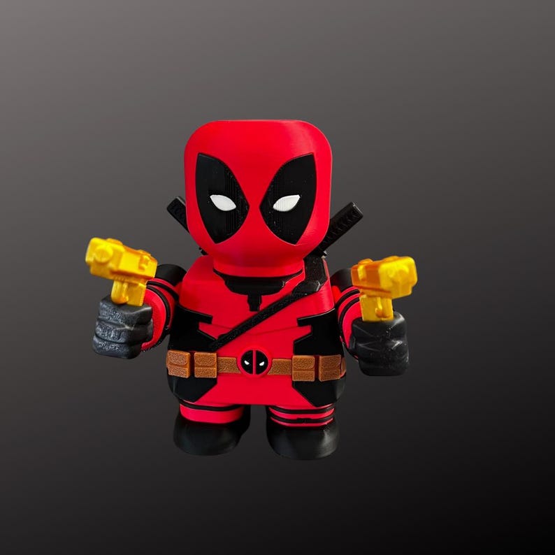 K&ouml;nnte beinhalten: Eine rot-schwarze Deadpool-Figur mit stilisiertem Design. Die Figur h&auml;lt zwei gelbe Spielzeugpistolen. Sie hat einen schwarzen G&uuml;rtel mit Deadpool-Logo und schwarze Handschuhe. Die Figur hat ein schwarz-rotes Farbschema.