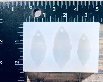 May include: A white silicone mold with three leaf-shaped cavities. Each cavity has a small hole at the top for hanging.