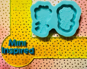 May include: Two-part silicone mold for making resin crafts. The mold is light blue and features two bear-shaped cavities. Each bear has a bow on its head and is holding a heart.