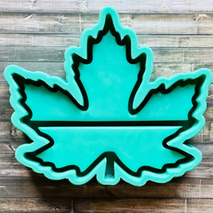May include: A teal green silicone mold shaped like a maple leaf with a black outline. The mold is designed to create a resin piece with a flat, horizontal section in the center.