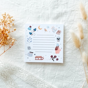 Puede incluir: Bloc de notas cuadrado con temática invernal. El bloc de notas presenta ilustraciones de mitones, un gorro, copos de nieve, un pájaro, una bola de nieve y un trineo. El bloc de notas tiene páginas rayadas para escribir.