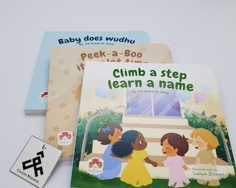 May include: Three children's books with titles including "Baby does wudhu", "Peek-a-Boo", and "Climb a step learn a name". The books have colorful illustrations of children. A small white card with black text that reads "OUDH MANIA" is also present.