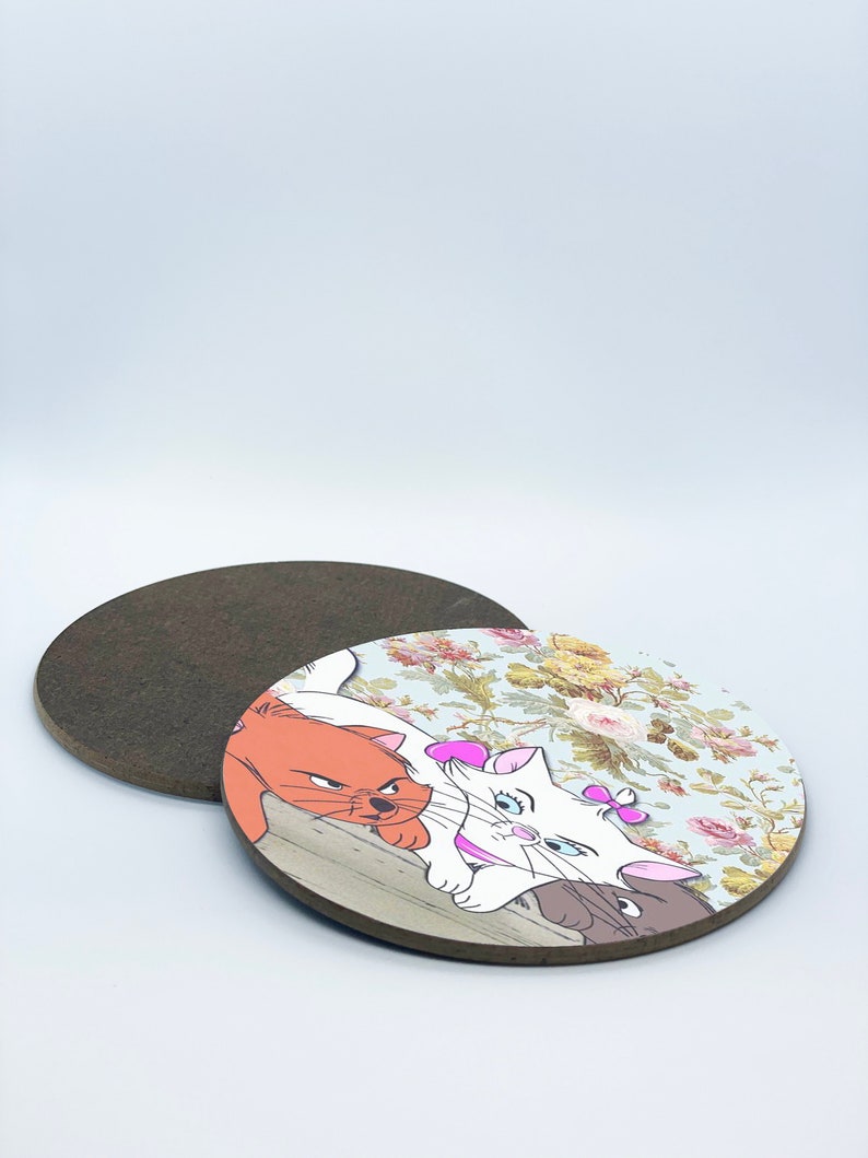 May include: Two cartoon cats, one white and one orange, are lying on a wooden surface with a floral background. The white cat has a pink bow on its ear. A brown mouse is peeking out from behind the cats.