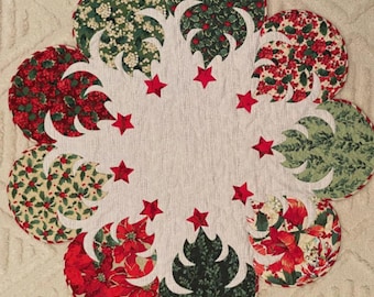 May include: A festive Christmas table runner featuring a floral design with red poinsettias, green holly, and red star accents. The runner is made of fabric and has a scalloped edge, perfect for holiday decor.