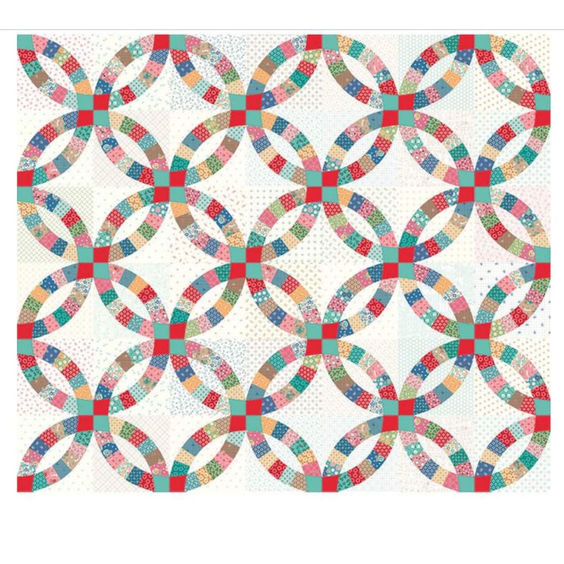 May include: A colorful quilt featuring a double wedding ring pattern. The design incorporates various patterned fabric squares in a circular arrangement, with red and teal accents. The background is a light, dotted fabric.