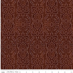 May include: A deep brown fabric featuring a repeating damask pattern outlined in thin, light-colored stitching. A white ruler is visible at the bottom edge, showing measurements in inches from 1 to 11, with the text Riley Blake Designs.