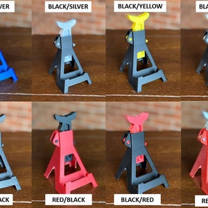 May include: Eight miniature car jack stands in different color combinations. The stands are made of plastic and have a silver metal hook. The colors include blue, black, yellow, white, red, and silver.